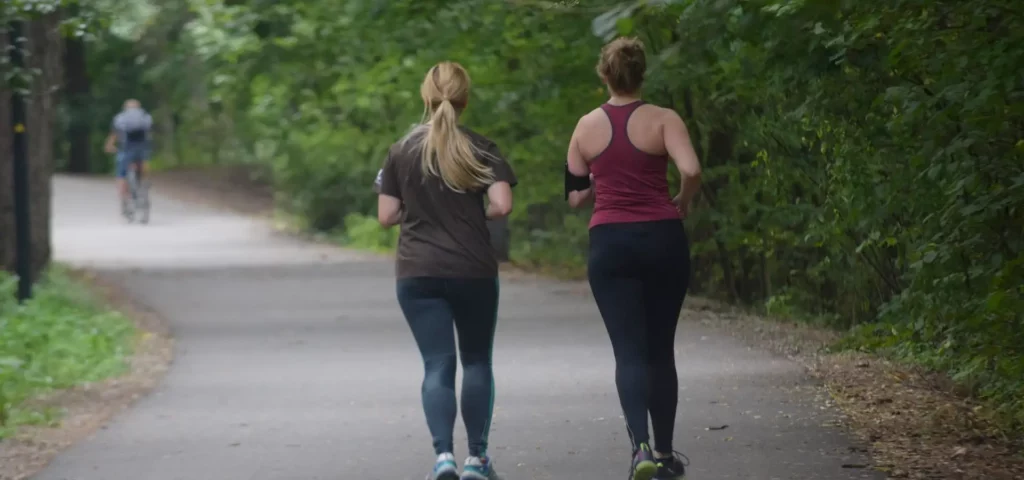 Zwei Personen joggen auf einem Waldweg.