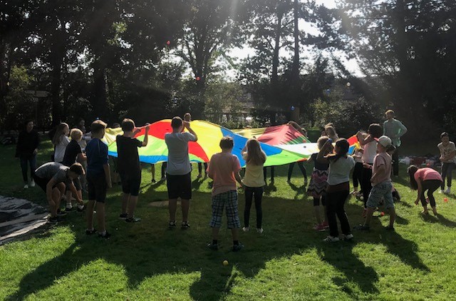 Gruppe von Menschen spielt mit einem Fallschirm im Park.