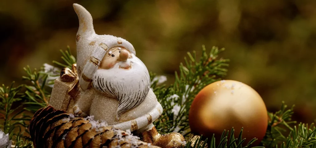 Weihnachtliche Figur zwischen Tannenzweigen und Kiefernzapfen.