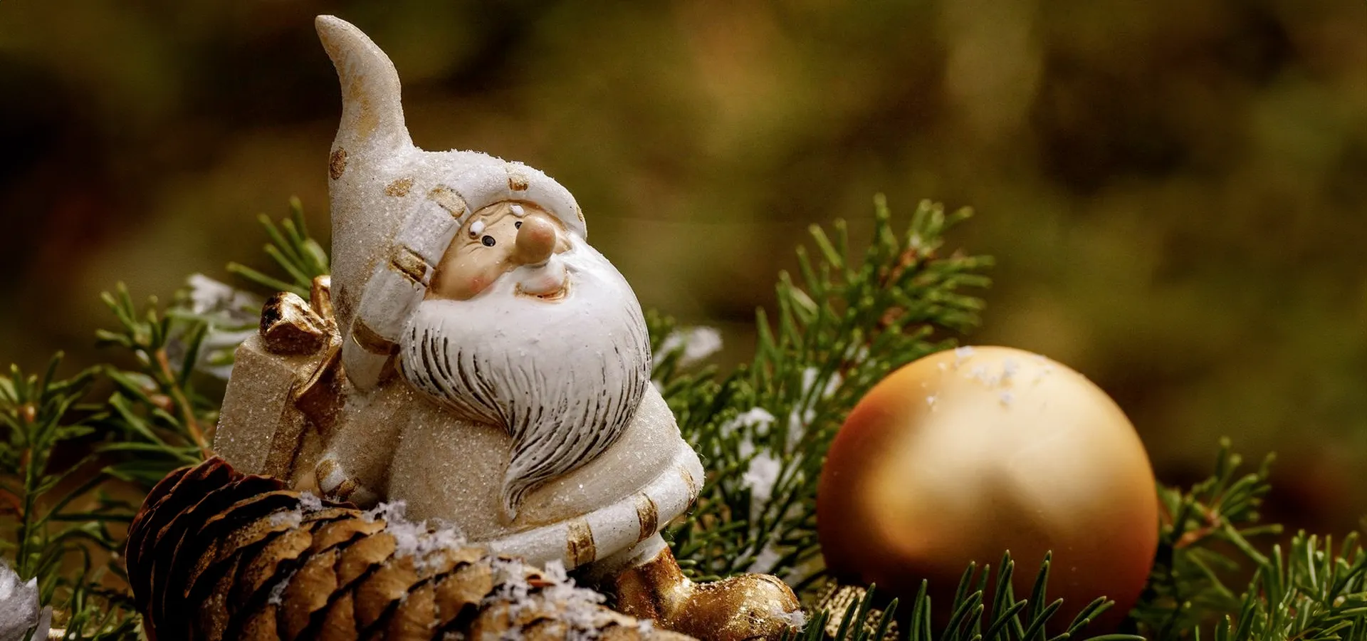 Weihnachtliche Figur zwischen Tannenzweigen und Kiefernzapfen.