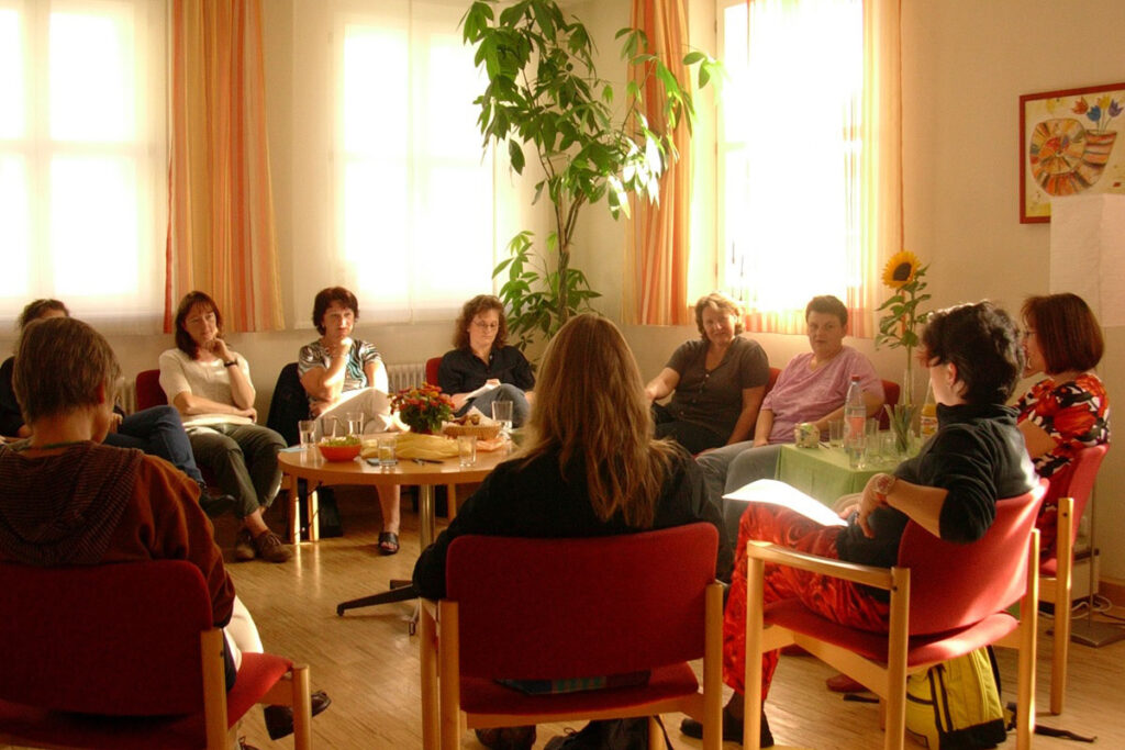 Gruppe von Menschen sitzt im Kreis bei einer Besprechung.