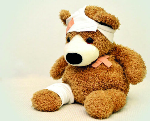 Ein Teddybär mit verbundenem Kopf und Bein und Pflaster auf der Brust