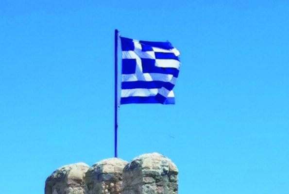 Eine griechische Flagge weht auf einer Burgspitze